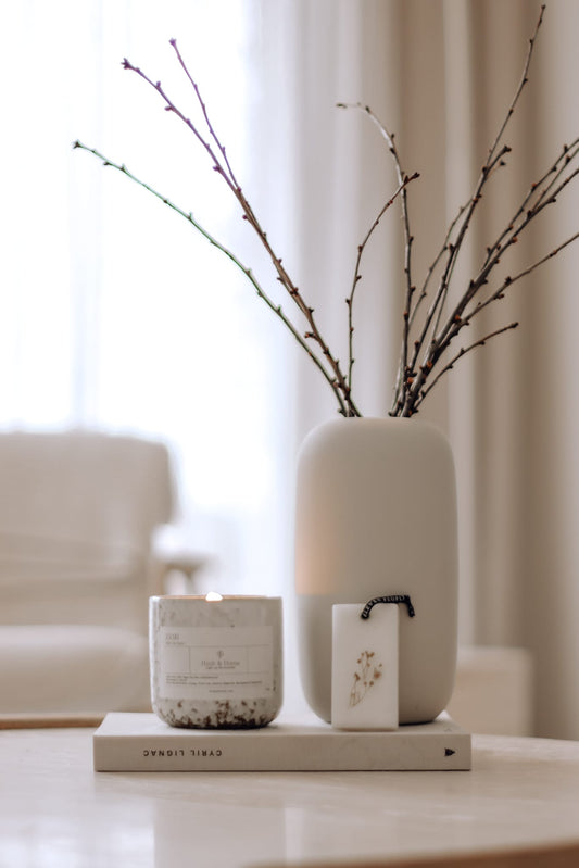 White vase with branches on a table with a blurred background